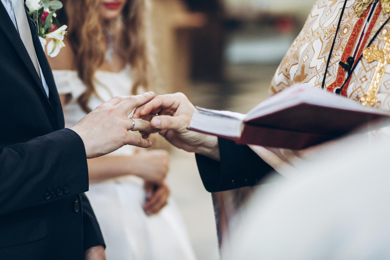  priest putting on wedding rings on groom and bride